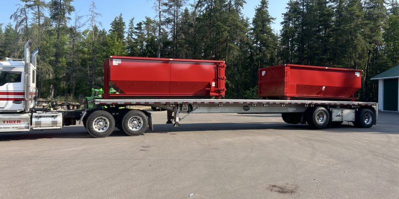 Two 20 yard dumpsters on a flatbed of a truck.