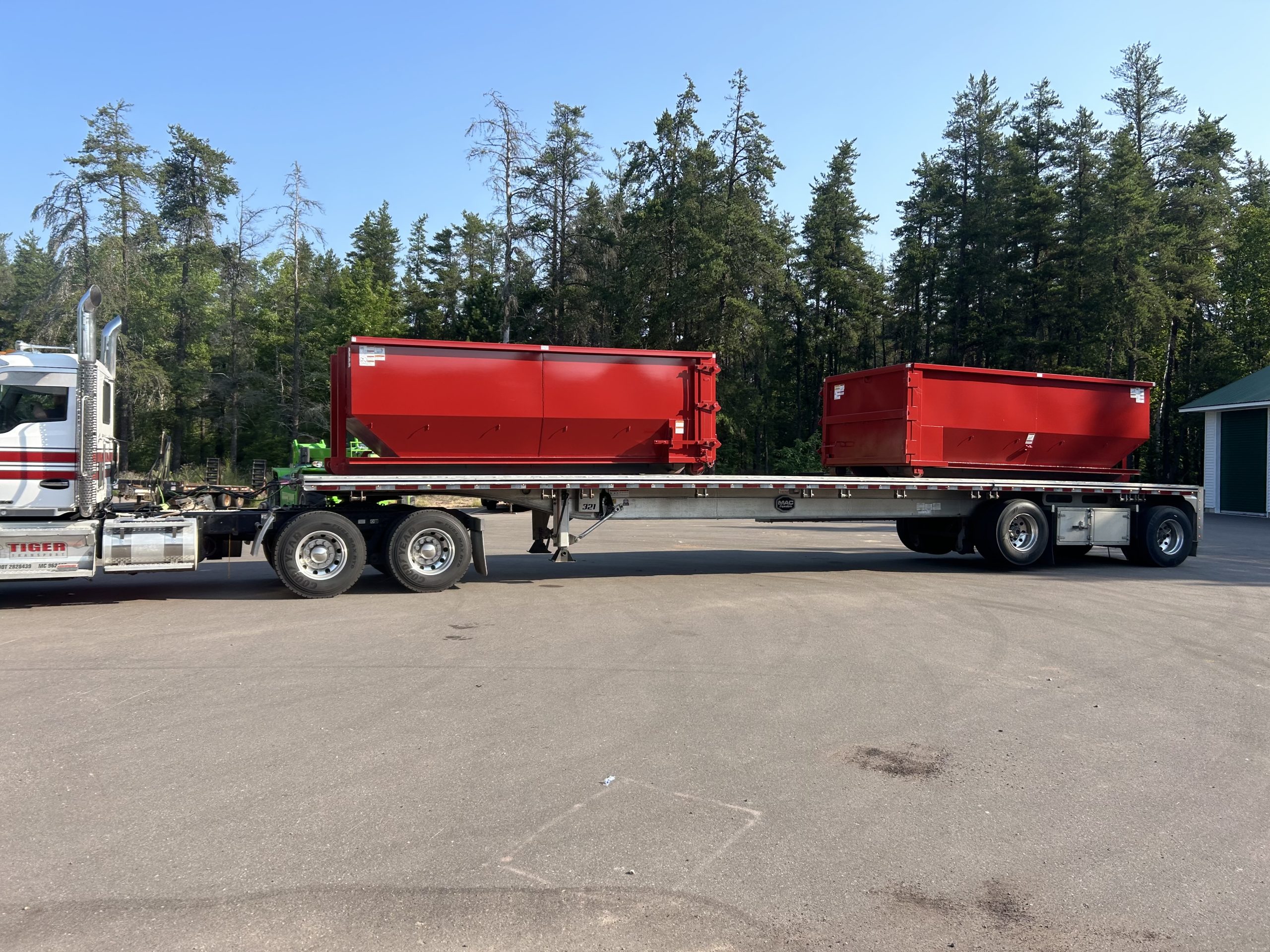 Two 20 yard dumpsters on a flatbed of a truck.