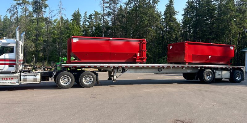 Two 20 yard dumpsters on a flatbed of a truck.